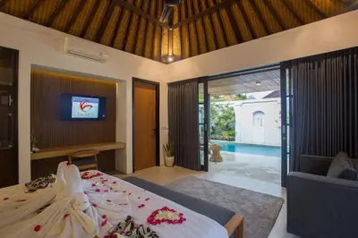 a bedroom with a bed and a tv on a wall at The Kon's Villa Bali Seminyak in Seminyak