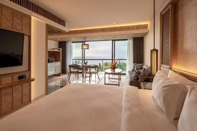 a bedroom with a large bed and a living room at AYANA Segara Bali in Jimbaran