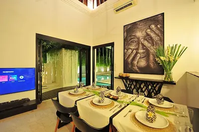 a dining room with a table with chairs and a tv at Villa Zensa @ The Residence Seminyak in Seminyak
