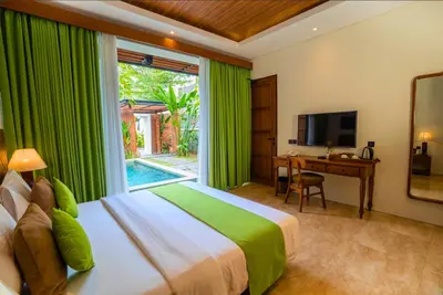 a bedroom with a bed and a desk and a television at Villa Bulan Bali in Jimbaran