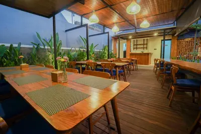 a restaurant with wooden tables and chairs and plants at Villa Bulan Bali in Jimbaran