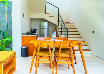 a dining room with a table and chairs and stairs at Villa Bulan Bali in Jimbaran