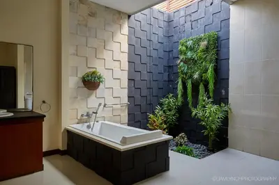 a bathroom with a bath tub with a plant wall at Villa Nicola in Seminyak