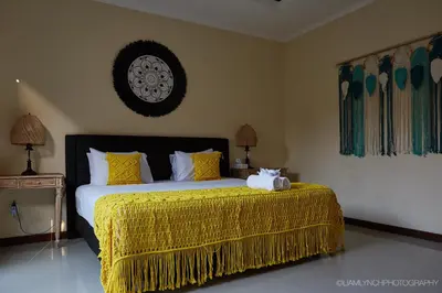 a bedroom with a large bed with a yellow bedspread at Villa Jae in Seminyak