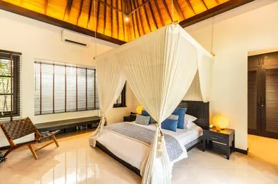 a bedroom with a bed with a mosquito net at PROMO Tropical 3 BD Villa with office and parking in Kerobokan