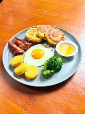 a plate of breakfast food with eggs bacon and other foods at Rahayu Guest House Seminyak in Seminyak