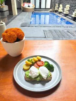 a plate of food with eggs and vegetables on a table at Rahayu Guest House Seminyak in Seminyak