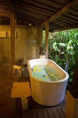 a bath tub sitting on a wooden deck with at Wahyu lux honeymoon joglo 2 in Seminyak