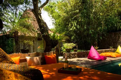 a table and chairs with colorful pillows on a patio at Wahyu lux honeymoon joglo 2 in Seminyak