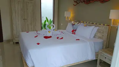 a bedroom with a white bed with red flowers on it at Kubu Garden Suites & Villas Nusa Dua in Nusa Dua