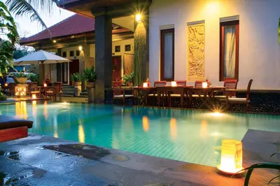 a swimming pool with a table and chairs next to a house at Kubu Garden Suites & Villas Nusa Dua in Nusa Dua