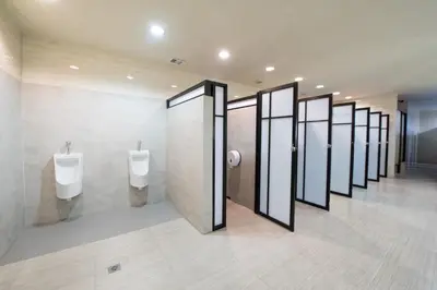 a row of stalls in a restroom with urinals at PassGo Digital Airport Hotel Bali in Kuta