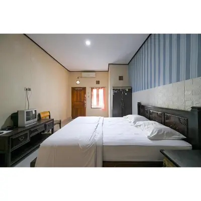 a bedroom with a large bed and a television at Pondok Syariah Denpasar Mitra RedDoorz in Kerobokan