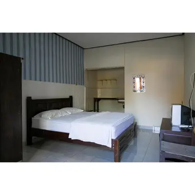 a bedroom with a bed and a desk and a television at Pondok Syariah Denpasar Mitra RedDoorz in Kerobokan