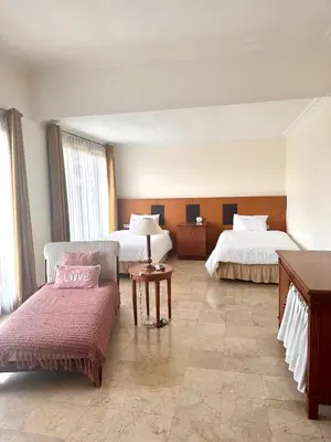a hotel room with two beds and a couch at Turtledove Guesthouse in Kerobokan