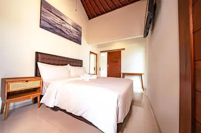 a bedroom with a white bed and a wooden night stand at 5 BR Villa Sultan Luxury Entertainment and Relaxation in Seminyak