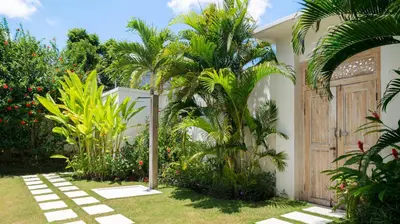 a garden with palm trees and a wooden door at Villa Aloui by Villa Finder in Kerobokan