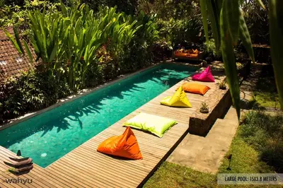a row of colorful pillows sitting next to a swimming pool at Luxury 4BR Villa with 2 Pools & Garden in Seminyak