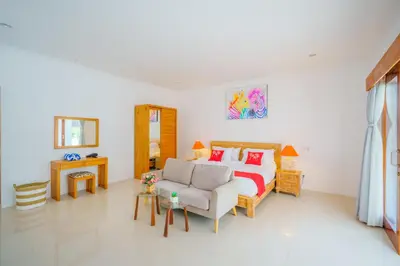 a bedroom with a bed and a couch and a chair at Selog Seven in Seminyak