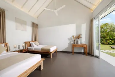 a bedroom with two beds and a large window at Villa Swarna by Nakula in Seminyak