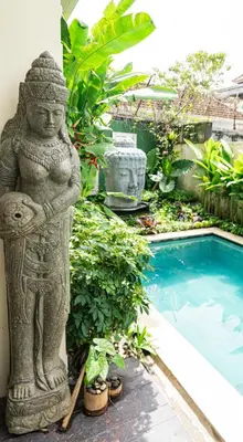 a statue next to a swimming pool in a garden at Villa Tepi Sungai - 6BR Luxury Private Pool Villa - Seminyak Sleeps 14 in Legian