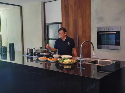 a man standing in a kitchen preparing food at Wahyu wonderful private honeymoon joglo in Seminyak