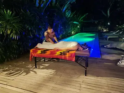 a man laying on a bed in front of a pool at Wahyu wonderful private honeymoon joglo in Seminyak