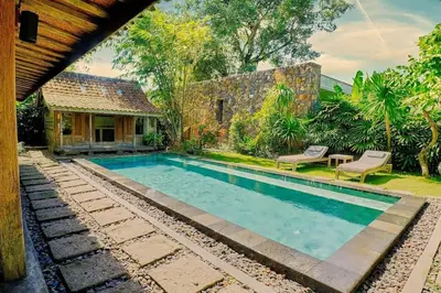 a swimming pool in front of a house at Wahyu wonderful private honeymoon joglo in Seminyak