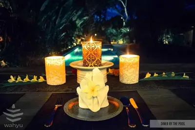 a table with candles and a plate with a flower on it at Wahyu wonderful 2Bd villa with huge garden and large pool in Seminyak