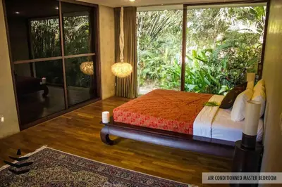 a bedroom with a bed and a large window at Wahyu wonderful 2Bd villa with huge garden and large pool in Seminyak