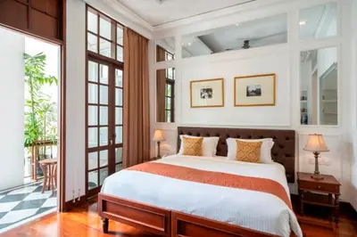 a bedroom with a large bed in a room with windows at The Colony Hotel Bali in Seminyak