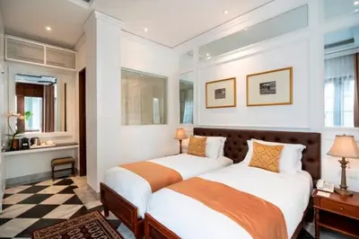 a bedroom with two beds and a checkered floor at The Colony Hotel Bali in Seminyak