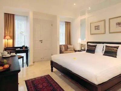 a bedroom with a large white bed and a desk at The Colony Hotel Bali in Seminyak