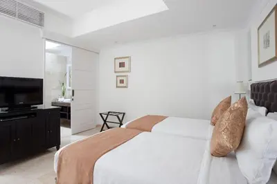 a white bedroom with a bed and a flat screen tv at The Colony Hotel Bali in Seminyak