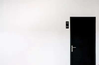 a black door with a sign on it next to a wall at Guyana Hotel in Kuta