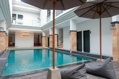 an indoor pool with umbrellas in a building at Guyana Hotel in Kuta