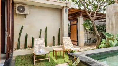 a patio with two chairs and a swimming pool at Cosy and Cheerful 2 Bedroom villa 5mins to Finns in Canggu