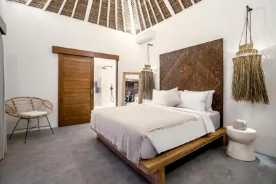 a bedroom with a large bed and a chair at Villa Cocotier by Alfred in Bali in Seminyak