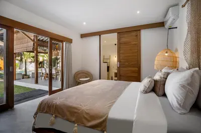 a bedroom with a large bed and sliding glass doors at Villa Cocotier by Alfred in Bali in Seminyak