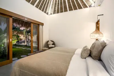 a bedroom with a bed in a room with a window at Villa Cocotier by Alfred in Bali in Seminyak