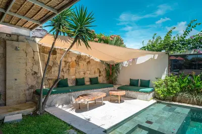 a patio with a couch and a table next to a pool at Villa Elma - Huge 2-bedroom pool villa in Umalas! in Seminyak