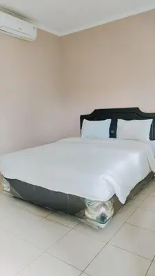 a large white bed sitting in a room at PURNAMA HOUSE KUTA in Kuta
