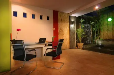 a room with a desk with chairs and a laptop at Valomia Guest House in Kerobokan
