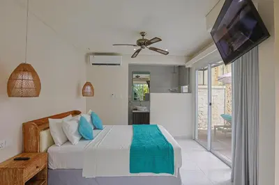 a bedroom with a bed with a ceiling fan and a television at Lacasa2 Villa Legian With Butler in Legian