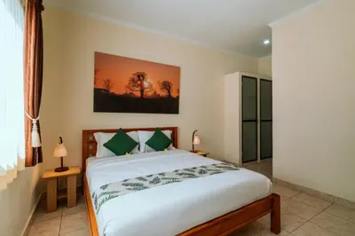 a bedroom with a large white bed with green pillows at Umah Kita in Seminyak