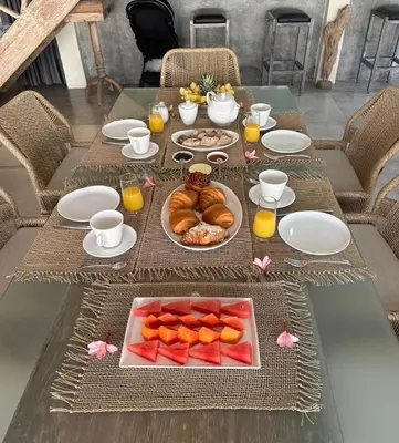 a table with plates of food and fruit on it at Villa Amana Seminyak in Seminyak