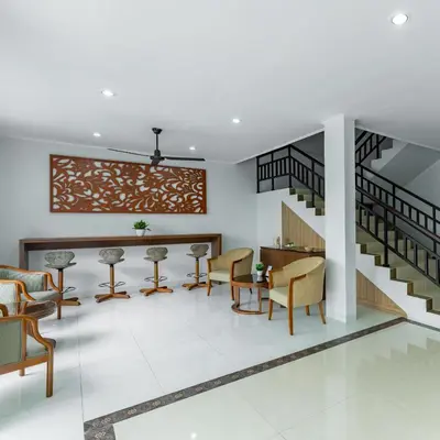 a lobby with chairs and a table and stairs at Cove Matahari Guesthouse Sunset in Legian