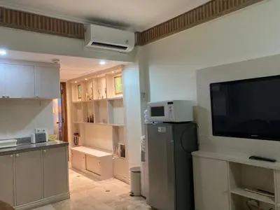 a kitchen with a flat screen tv and a kitchen with a refrigerator at Coastal Suite at Jayakarta Residence in Seminyak
