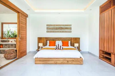 a bedroom with a wooden bed with orange pillows at Canggu 400m to Beach Escape 4br Designer villa in Canggu
