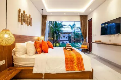 a bedroom with a bed with orange pillows and a tv at Canggu 400m to Beach Escape 4br Designer villa in Canggu